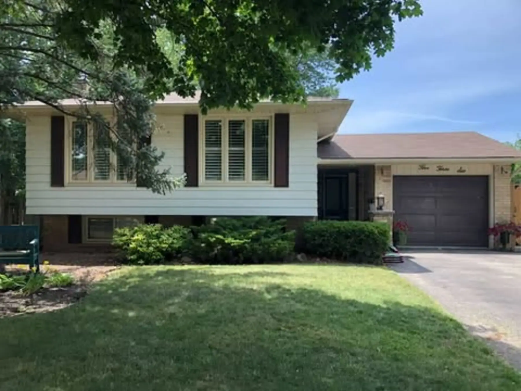 Original Burlington bungalow before its second-storey addition, with beige siding, brown shutters and attached garage