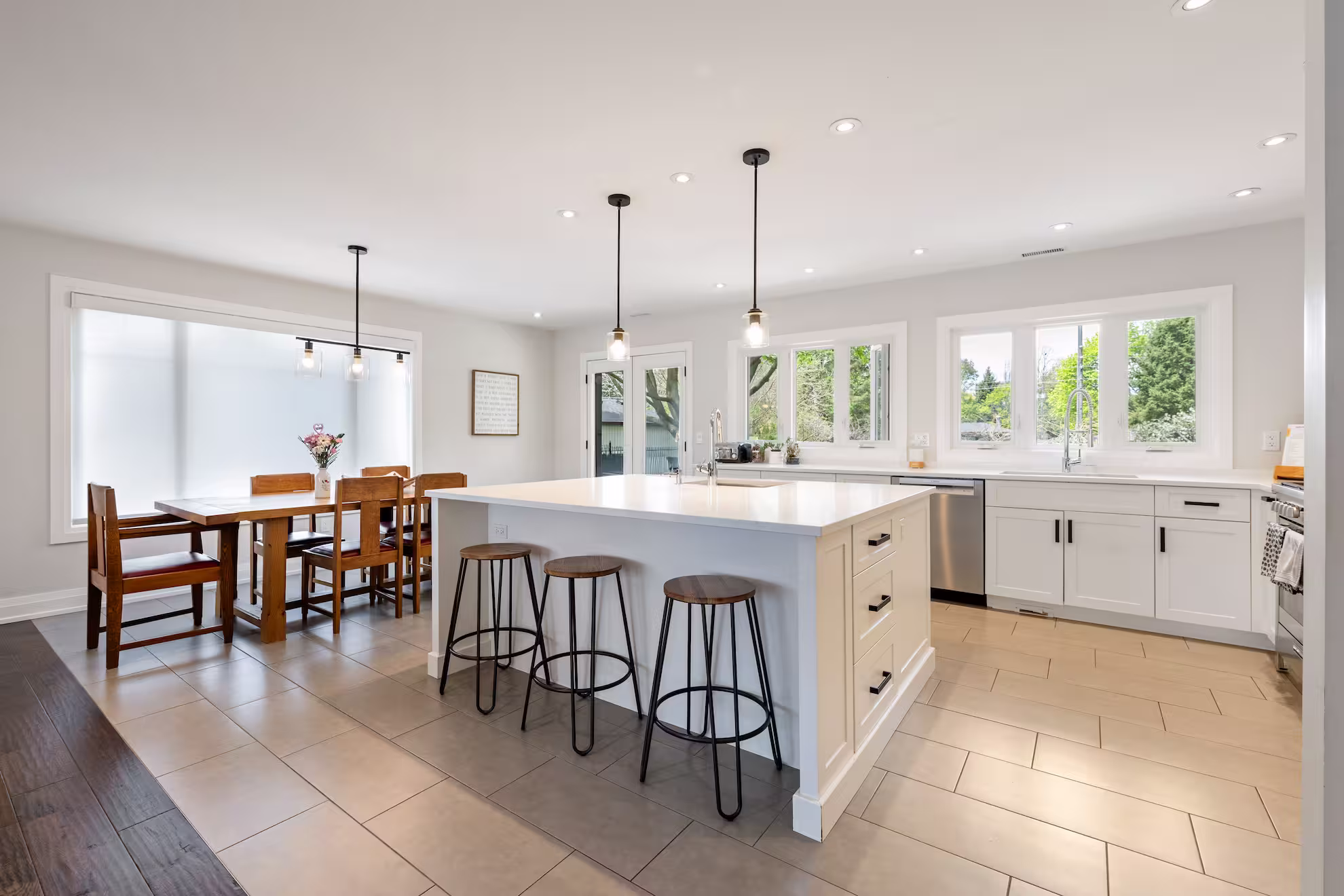 White kitchen with large quartz island, pendant lights and adjoining dining area, Burlington full home transformation