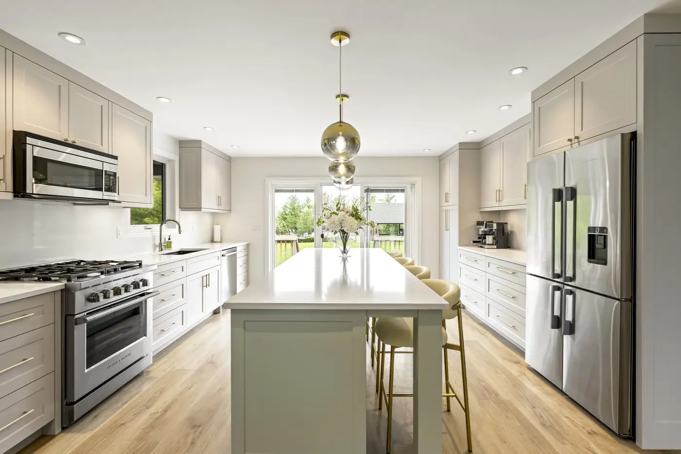 Renovated kitchen with a sage green island, pendant lighting and stainless steel range opening onto a bright dining area