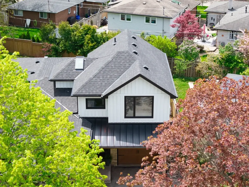 Aerial view of a home with a steep gabled roof surrounded by mature trees