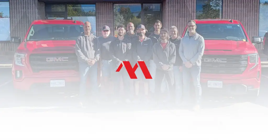The Marcon Construction team standing in front of their red company trucks, with the Marcon logo