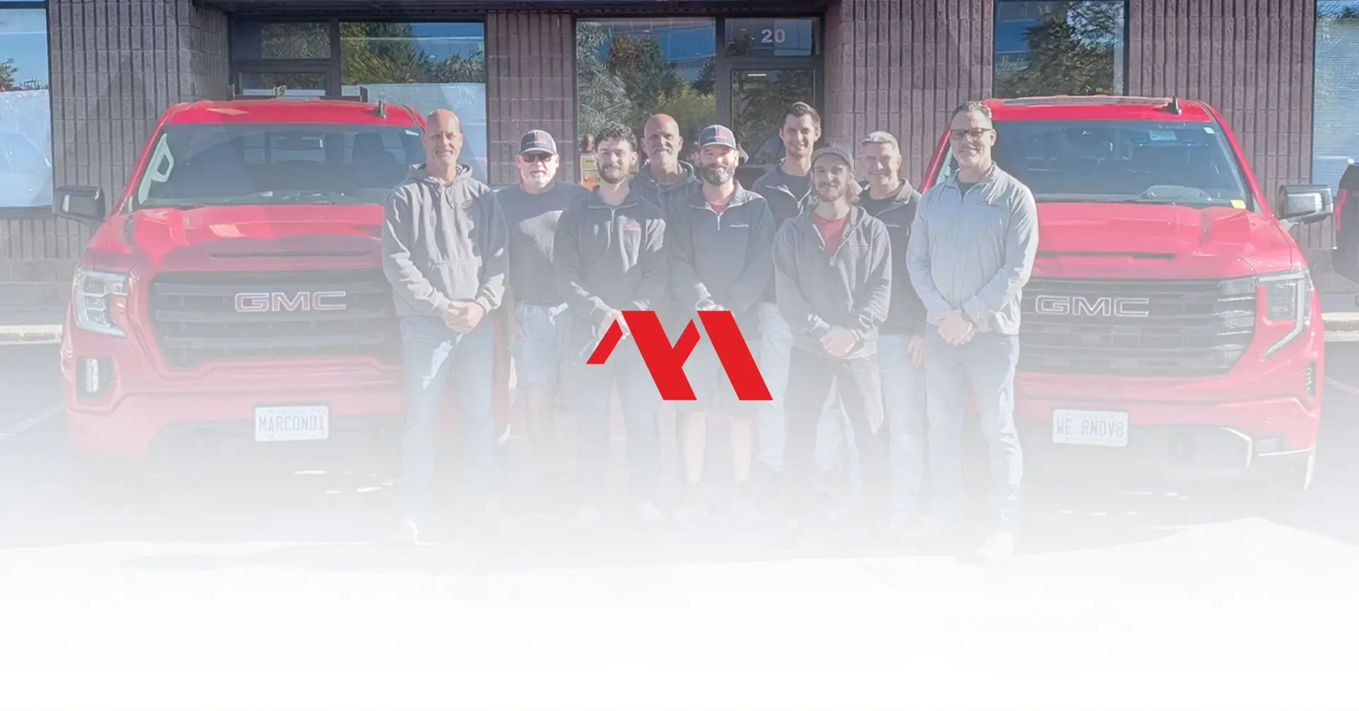 The Marcon Construction team standing in front of their red company trucks, with the Marcon logo