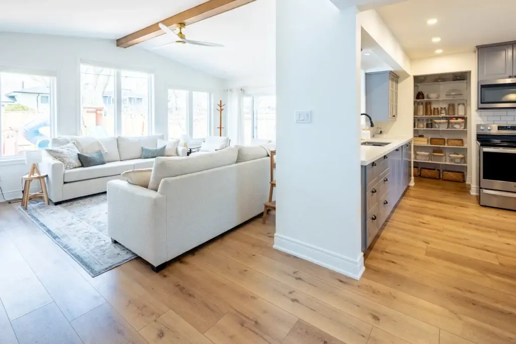 Open living area with a white sectional and area rug, looking through to the kitchen