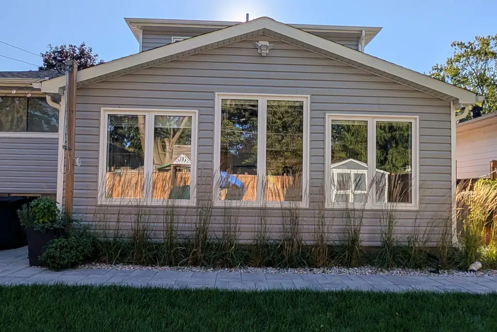 Back of a two-storey Burlington home with grey siding and a new sunroom with large windows facing the yard