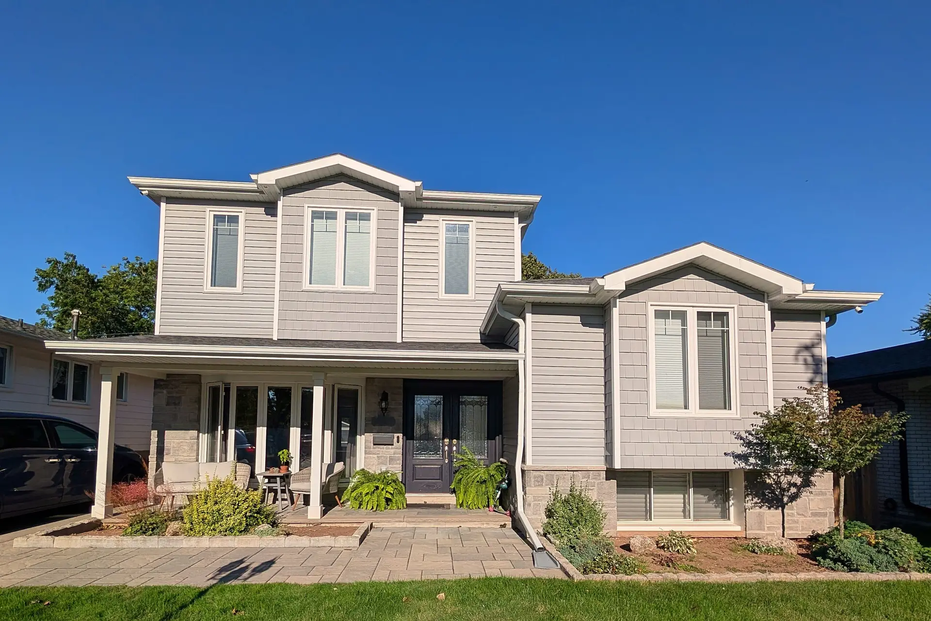 Two-storey Burlington home with grey siding, a covered front porch and a landscaped front yard after Marcon's second storey addition