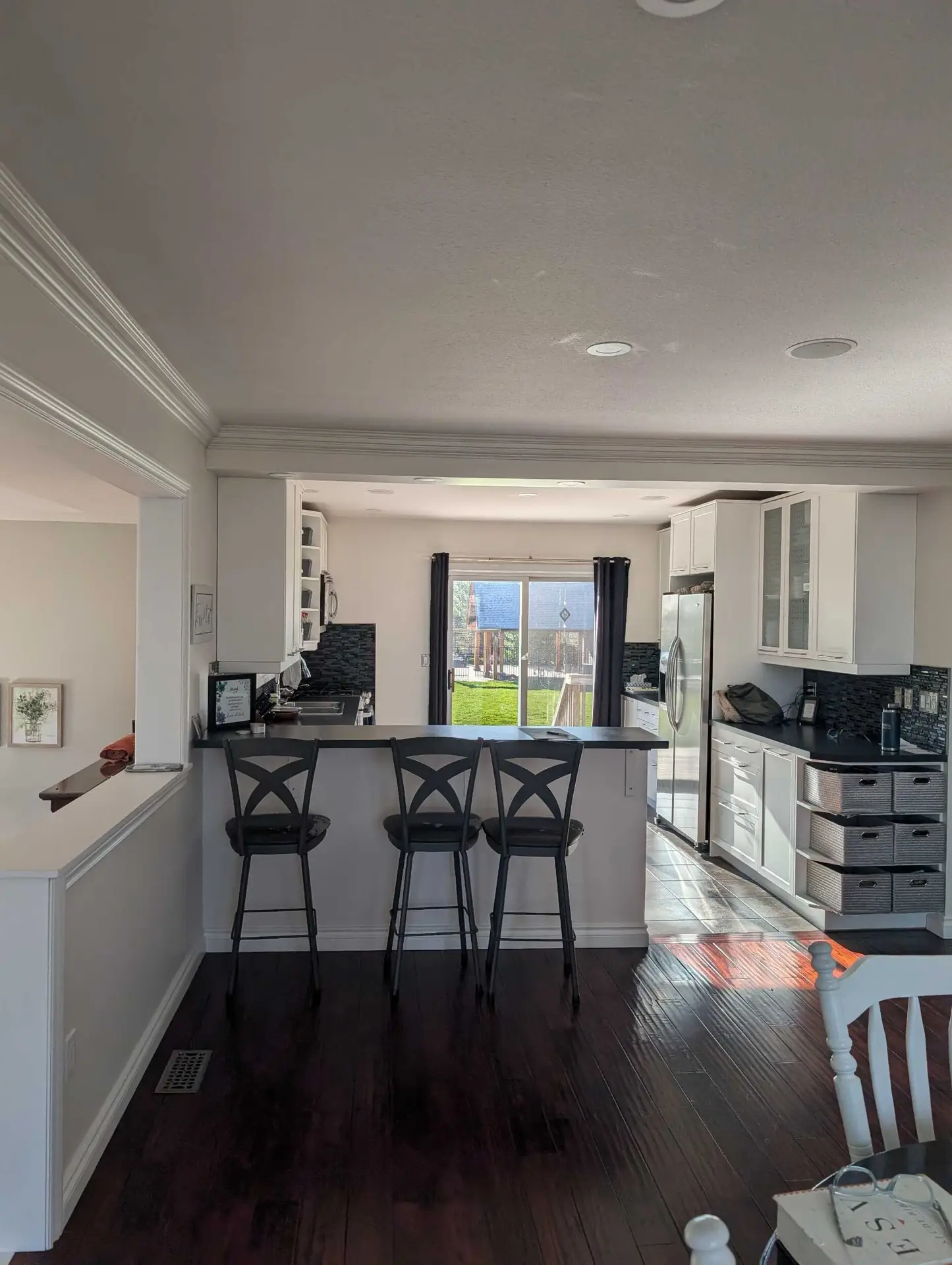 The original Grimsby kitchen before renovation, with dark hardwood floors, white cabinets and a raised breakfast bar