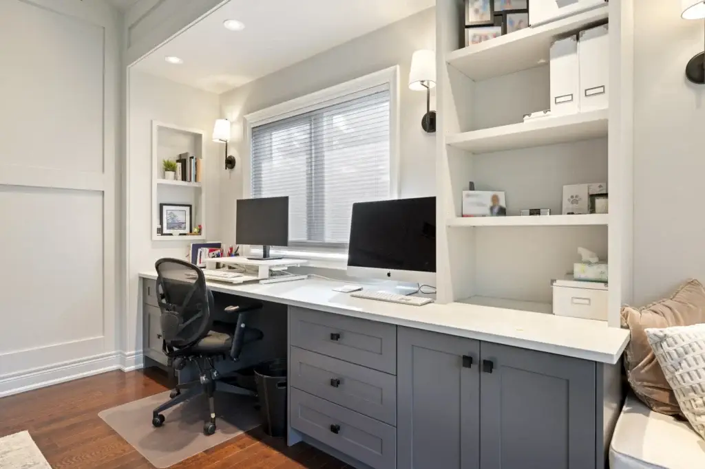 Home office with a long built-in desk, shelving and a wall-mounted heat pump
