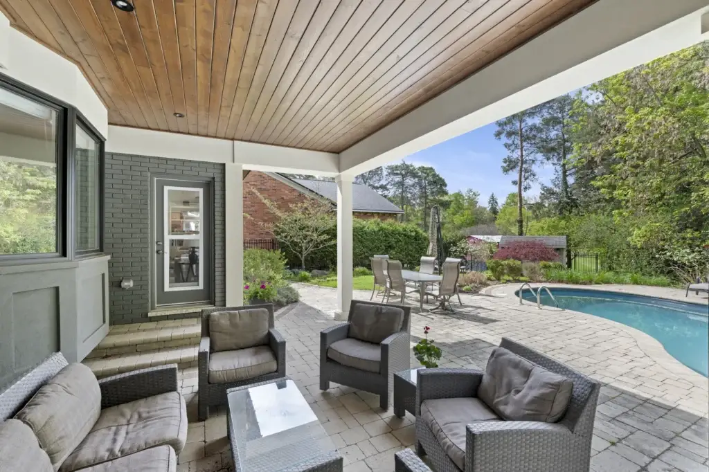 Covered patio with a wood ceiling looking out to the pool and garden