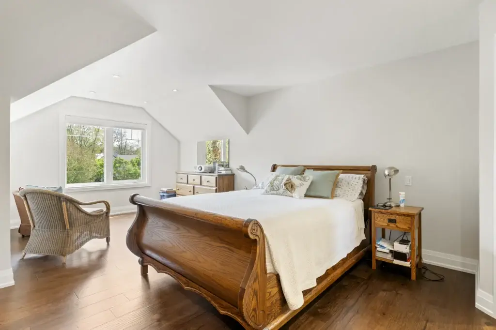 Bedroom with a wooden sleigh bed, dormer window and an upholstered bench