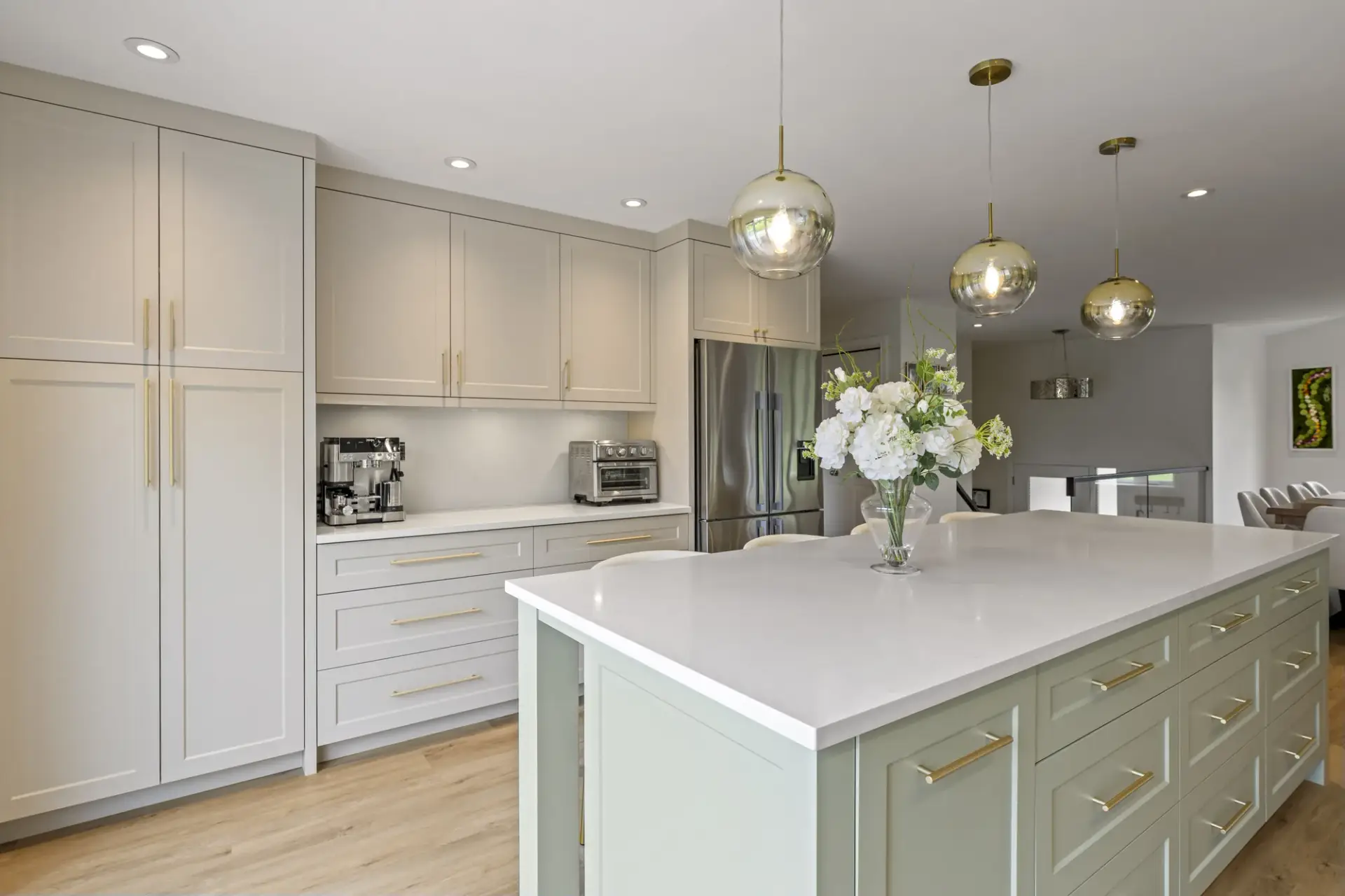 Kitchen with tall cream cabinetry, a sage green island and pendant lighting